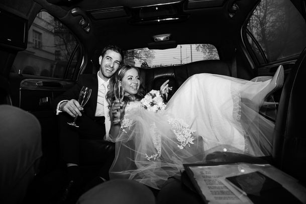 couple smiling while drinking ina limo on their wedding day. 