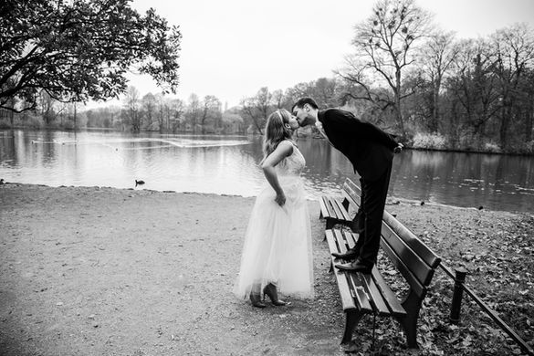 a couple by a river side posing for a photo on their wedding day. 