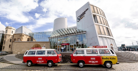 Zwei rote VW Bullis vor dem Gebäude des Schokoladenmuseums Köln