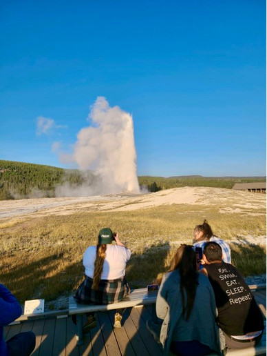 Guests take in the power of geyser eruption (from a safe distance!) in Yellowstone National Park
