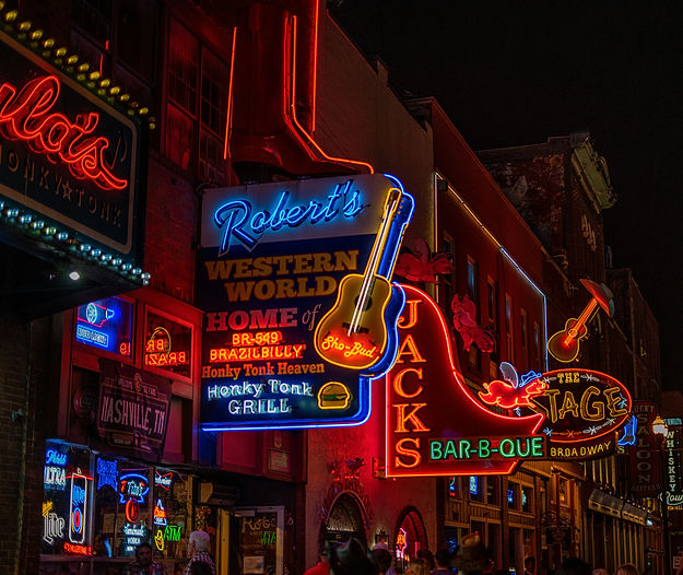 An image of the neon honky-tonk sign along an iconic nashville street lit up at night