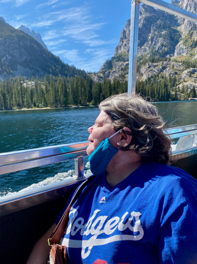 A guest smiles soaking in the sun gazing out over a scenic mountain lake