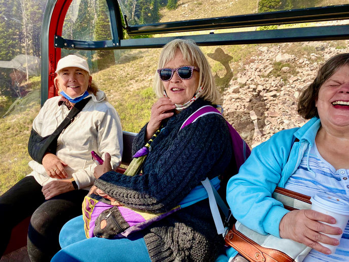 Three guests laugh and smile as they enjoy a scenic ride on the Jackson Hole gondola