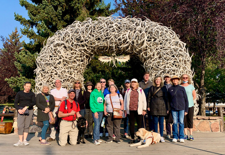 Our guests and guides gather for a group photo in front of Jackson Hole's Elk Antler Arch on a clear sunny mountain day.