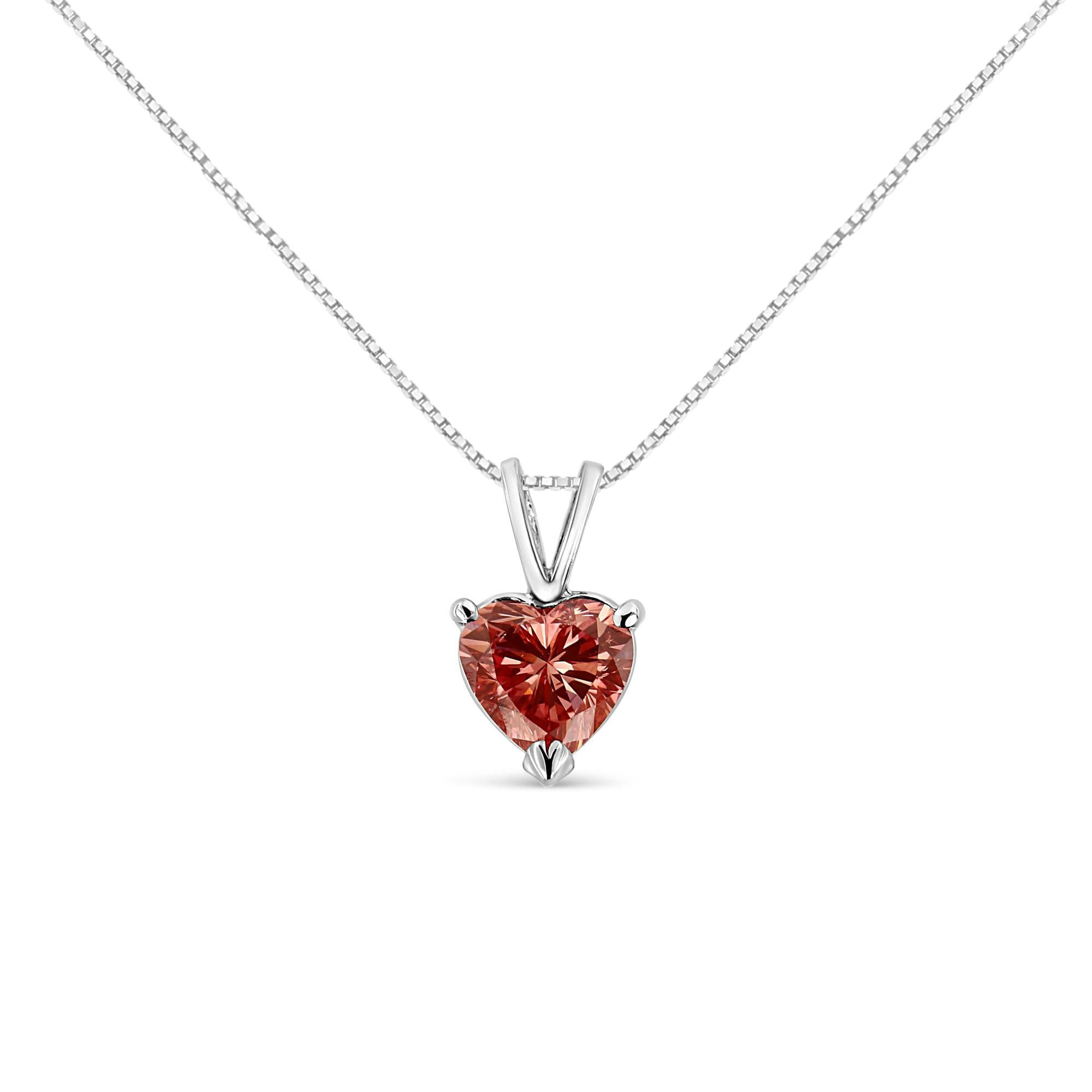 Silver necklace with a heart-shaped, red gemstone pendant on white background.