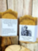 2 bars of soap sitting on pieces of wood in front of a wood background.