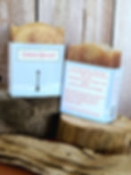 2 bars of soap sitting on pieces of wood in front of a wood background.