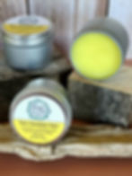 Three tins of Dandelion Salve, one open showing yellow contents