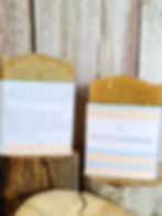 2 bars of soap sitting on pieces of wood in front of a wood background.