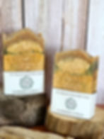 2 bars of soap sitting on pieces of wood in front of a wood background.