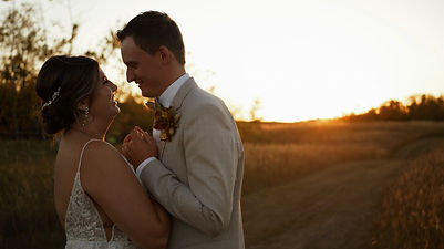 Bride and groom holding hands at sunset, gazing at each other