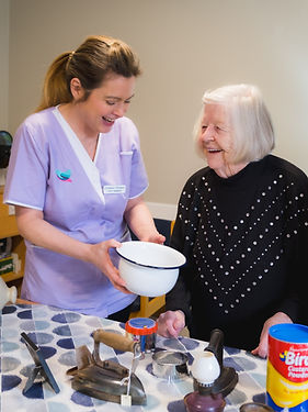 A resident and care assistant looking at objects from the past.