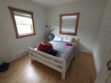 A bed in the middle of a white room. Kiera's suitcase is on top of it.