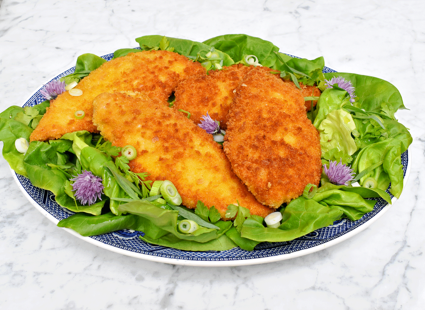 Chicken schnitzel on a green lettuce and herb salad