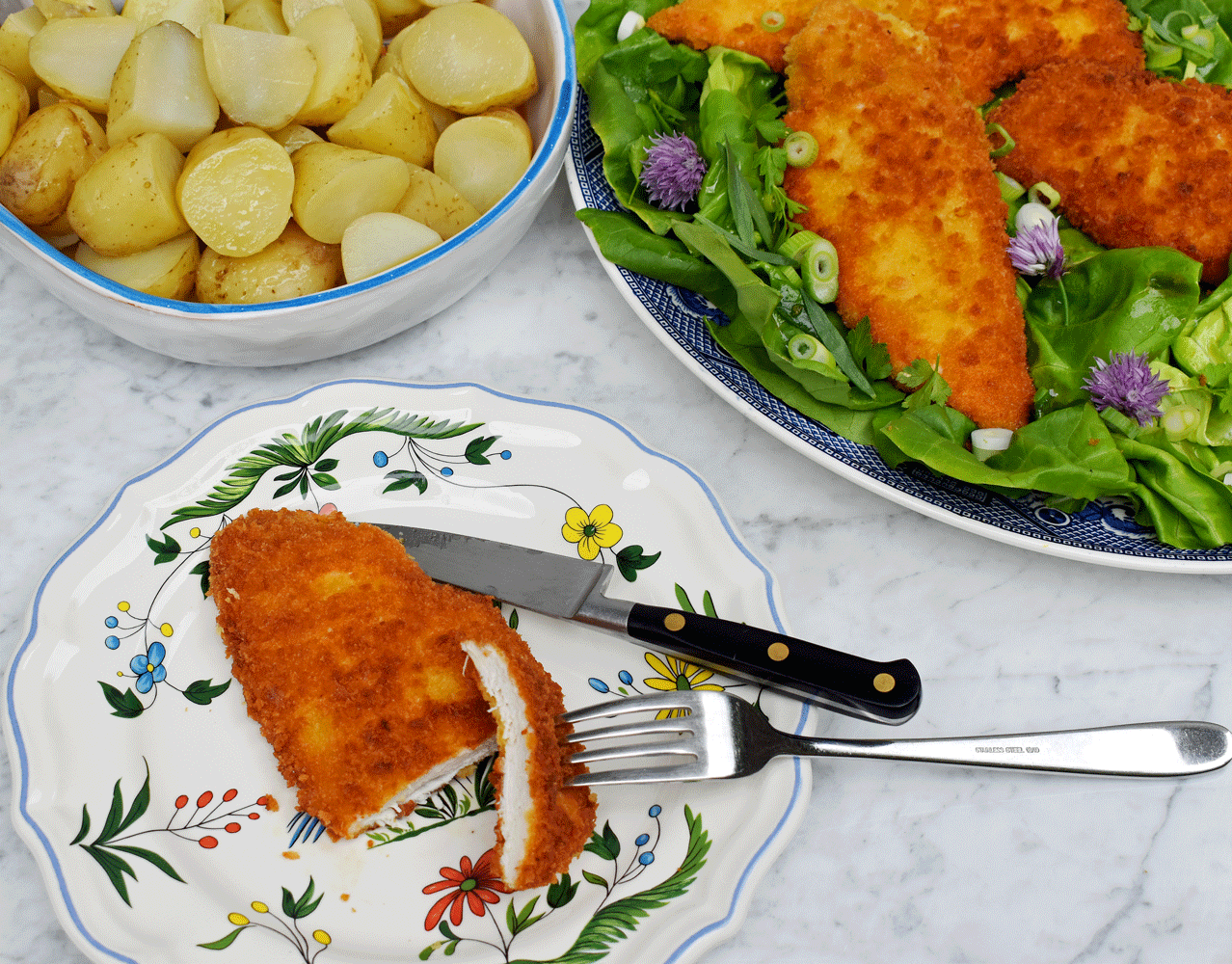 Chicken schnitzel on a green lettuce and herb salad