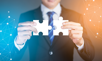 Un hombre en traje sosteniendo una pieza de puzzle, representando la integración empresarial y la expansión estratégica.