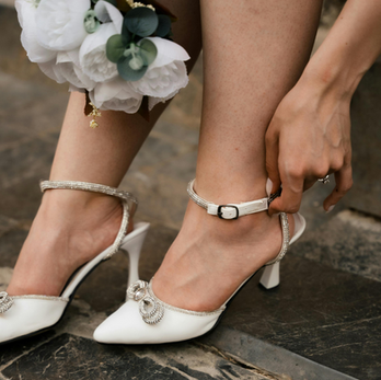 bride doing up her shoes with manicured nails