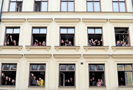 Ett gäng glada arbetskamrater tittar ut genom fönster och vinkar.