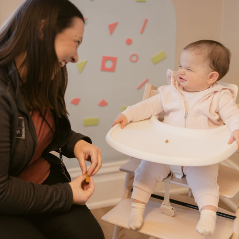 Child participating in feeding therapy session exploring new foods with therapist support in a pediatric clinic