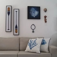 Salon rustique avec décoration murale en forme de rame, filet de pêche et accents nautiques, créant une atmosphère côtière chaleureuse avec des textures naturelles et des éléments inspirés de la mer.