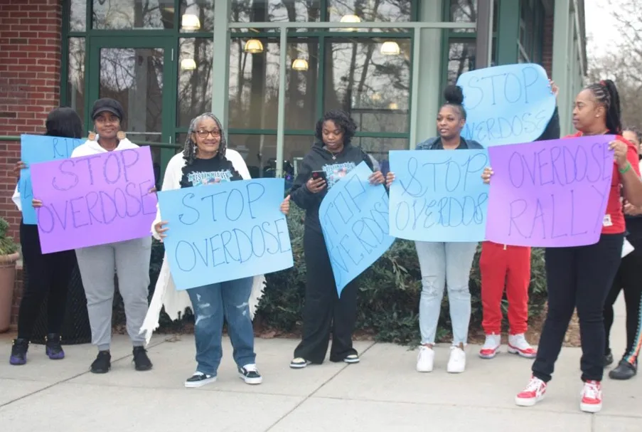 Participants hold signs during an overdose awareness rally at Freedom Park in Charlotte, North Carolina, in February 2024. The event was organized by Hajee House Harm Reduction, which focuses on addressing a surge in addiction and overdoses among Black people. (Sanchez Huntley)