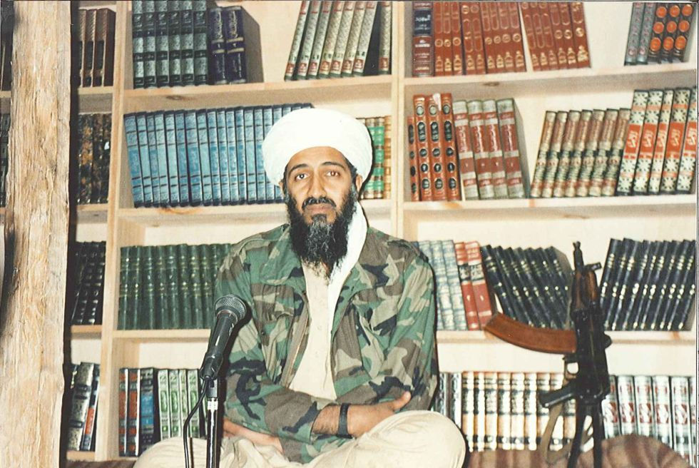 bin laden sentado ao lado de um fuzil