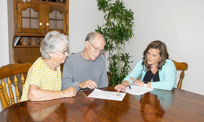 Professional woman consulting with senior couple at home