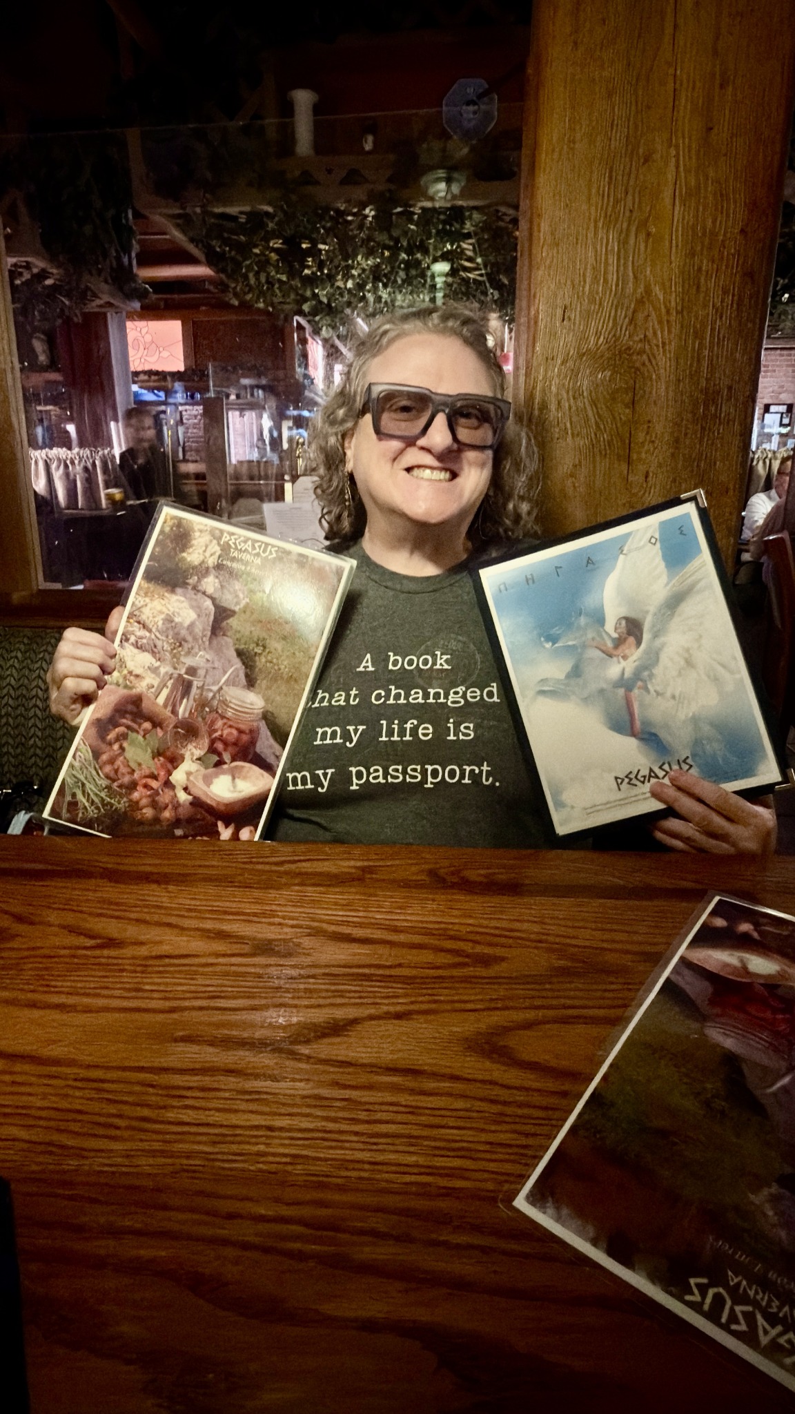 Natalie smiling with Pegasus Taverna menus during dinner in Detroit Greektown.