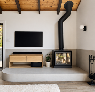 Modern living room with wood-burning fireplace, vaulted wood ceiling, floating media console, and minimalist interior design in Rockland County NY by Peluso Construction.