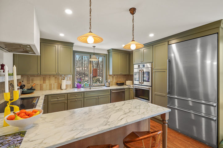 Elegant transitional kitchen remodel featuring olive cabinetry and warm wood flooring.
