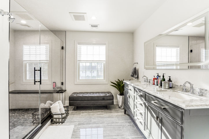 Luxury bathroom renovation in Rockland County featuring custom gray double vanity, marble countertops, frameless glass shower, large-format tile flooring, and modern spa-inspired finishes.
