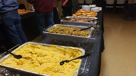 Custom catered event featuring cheesy potatoes, seasoned green beans, smoked meats and rolls.