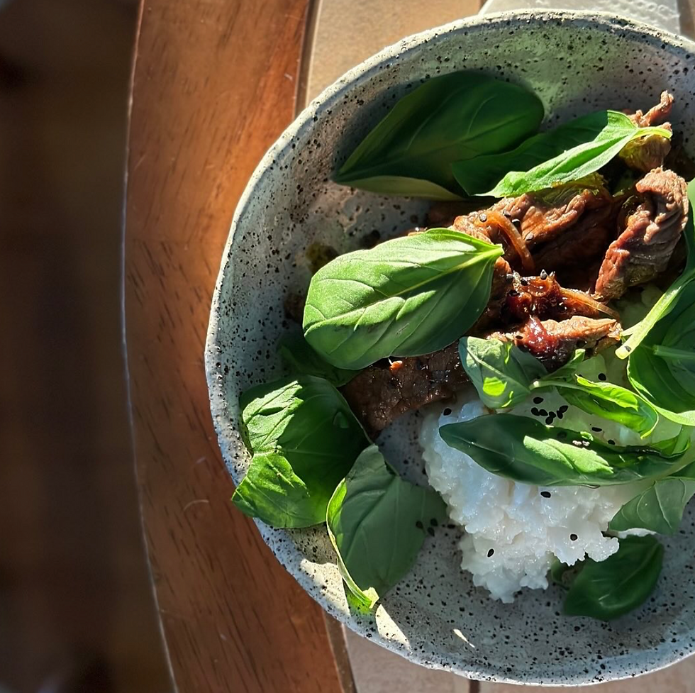 a bowl of congee with basil and beef