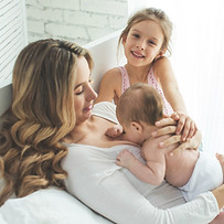Imagen de una madre cariñosa sosteniendo a su recién nacida mientras su hija pequeña observa con cariño, promoviendo nuestro servicio de perforación de orejas en la comodidad de tu hogar en Bucaramanga, Santander. En la Dra. Nini Pérez, nos comprometemos a brindarte un procedimiento seguro y conveniente para toda la familia. Confía en nosotros para hacer de este momento especial una experiencia tranquila y memorable.