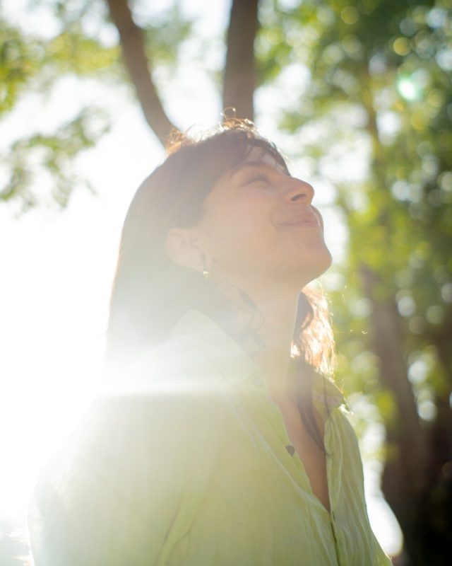 Frau hebt das Gesicht lächelnd in die Sonne