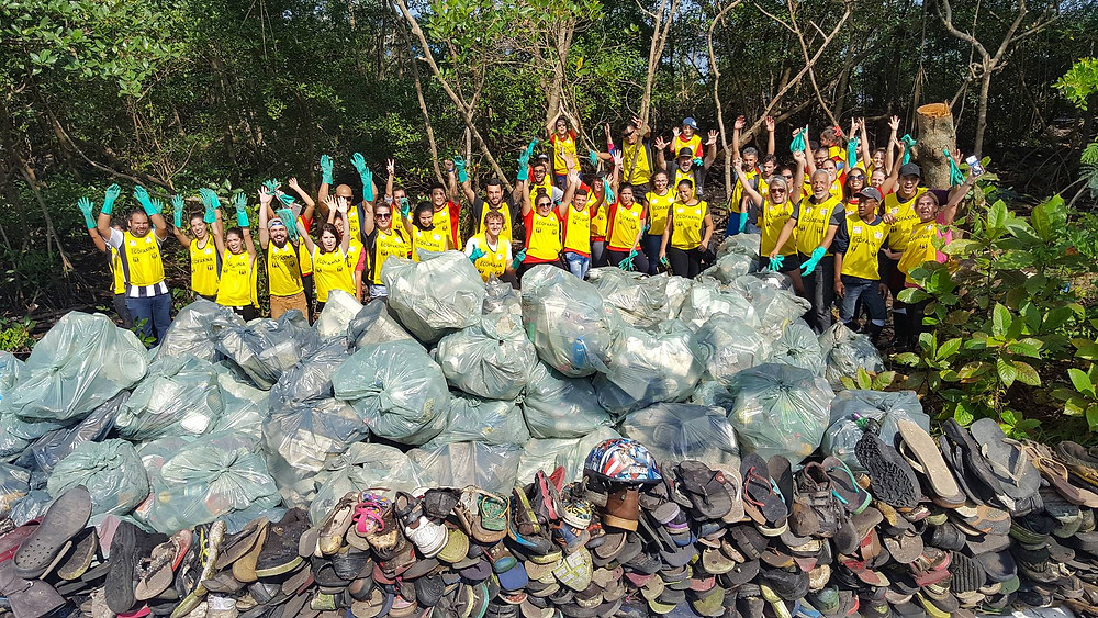 Voluntários posam para foto com os resíduos coletados no manguezal de Santos.