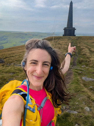 Woman pointing towards a large hilltop monument