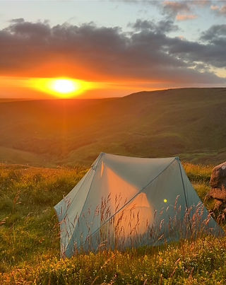 A tent on a hill at sunset