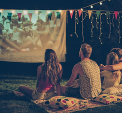 Outdoor Movie projected on a screen with four people sitting on a blanket