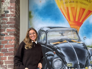 Teammitglied vor Akustikbild mit schwarzem Oldtimer, frontal fotografiert