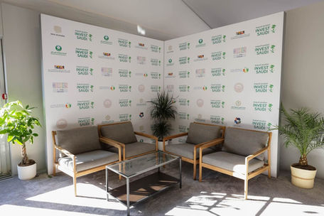 Lounge area with chairs and a table featuring Invest Saudi logos