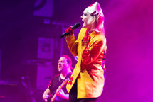 Performer singing on stage with vibrant lighting.