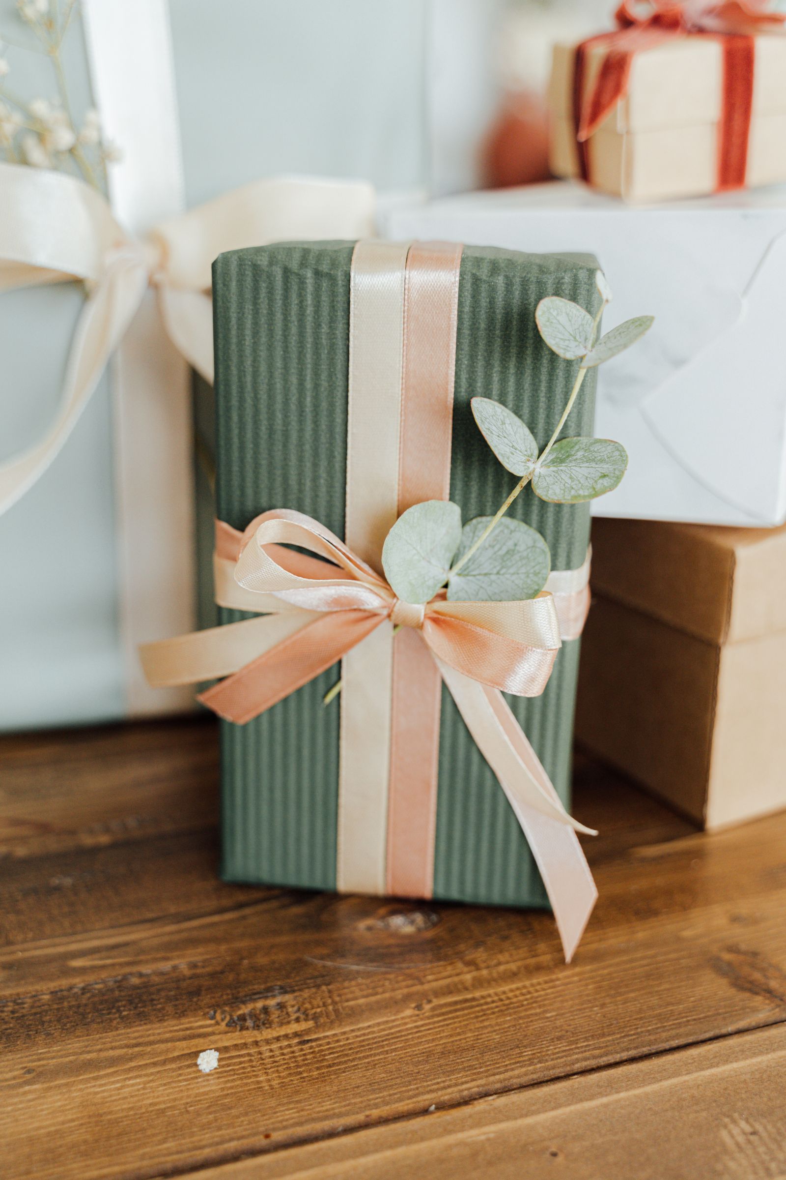 A wrapped gift with ribbon and eucalyptus leaves