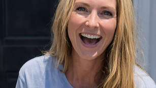 Blonde haired woman smiling in blue shirt.
