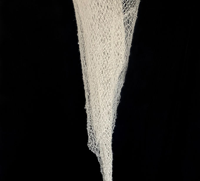 Kean University Galleries and Collections is pleased to announce a solo exhibition in the Karl and Helen Burger Gallery, Twisting Wool into Thread: Works by Marcy Chevali, on view September 8, 2026 through December 4, 2026. The opening reception for the artist will be held on Wednesday, October 14 from 5:30 – 7:30 P.M. in the Karl and Helen Burger Gallery. The Karl and Helen Burger Gallery, in the Maxine and Jack Lane Center for Academic Success, is open to the public Monday through Friday, 10:00 A.M. – 4:00 P.M.
In Marcy Chevali’s work, glass expands and contracts. Thin and transparent borosilicate glass rods are bent into shape with a torch and adjoined to form an irregular grid. These grids appear to swell, as if created around an invisible, dimensional form. Chevali refers to the structures she makes out of glass, metal, and sometimes mohair as “nets.” No matter the material, the treatment is similar; wire and mohair are likewise knotted or interlaced. Knotted mohair stiffens and becomes suspended in or imprinted on handmade abaca paper. Undulating wire nets anchor to the wall like spider webs or fishing trawls. Woolen veils, the length of the human body, trail from suspended ovoid vessels, pulled into funnel shapes under the force of gravity.
Chevali’s work develops slowly and methodically, calling to mind the story of Penelope’s web in Margaret Atwood’s novella The Penelopiad, from which the title of this exhibition is borrowed. According to Atwood’s reimagining of Homer’s Odyssey, Penelope must weave a shroud for her father-in-law Laertes, “twisting wool into thread.” Each natural fiber Chevali manipulates represents a calculated decision to fix material in place, allow it to move freely and respond to the environment, or remove it altogether.
Marcy Chevali lives and works in New York City and received her MFA from Maine College of Art and her BFA from the Ohio State University. Her work has been included in exhibitions at the Queens Museum of Art, Noyes Museum, Aicon Gallery, AIR Gallery, and Gallery Aferro, and with organizations such as South Asian Women’s Creative Collective, Hudson Valley Center for Contemporary Art, ABC No Rio, and Project for Empty Space. Chevali has participated in residencies at the Edward Albee Foundation, Haystack Mountain School of Craft, Urban Glass, Pittsburgh Glass Center, Monson Arts, and Willapa Bay AiR. She is a recipient of grants from the Queens Council of the Arts and FST Studio Projects.