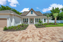 Charming house with brick driveway and lush landscaping.