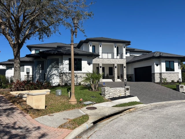 Modern two-story house with dark roof and driveway.