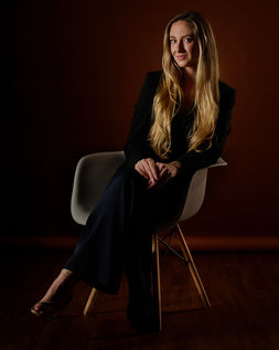 woman in black business suit sitting on chair posing for business