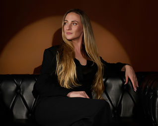 woman in black business suit sitting on black couch posing for business portrait