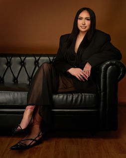 woman in black business suit sitting on black couch posing for business portrait